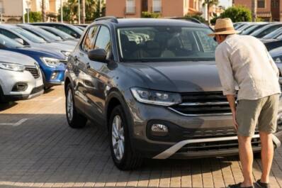 Cliente revisando un coche de segunda mano en un concesionario